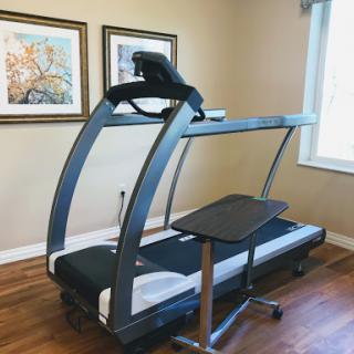 A treadmill designed for both exercise and workspace use, featuring a sleek design and adjustable components.