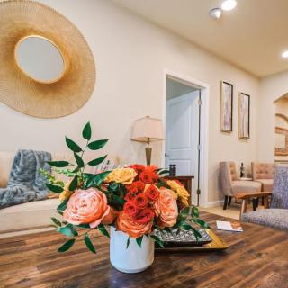 A stylish living room featuring a vase of vibrant flowers on a wooden coffee table, surrounded by cozy furniture and modern decor.