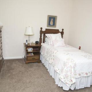 A traditional bedroom with a single bed, nightstand, and lamp.