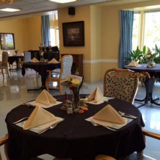 A dining room with elegantly set tables, featuring folded napkins and comfortable chairs.