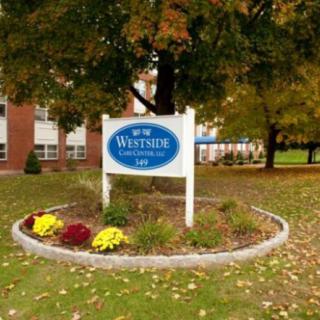 A school sign surrounded by autumn trees and landscaping.