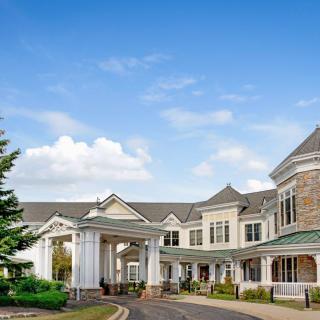 A large, elegant building with a grand entrance set against a blue sky with scattered clouds.