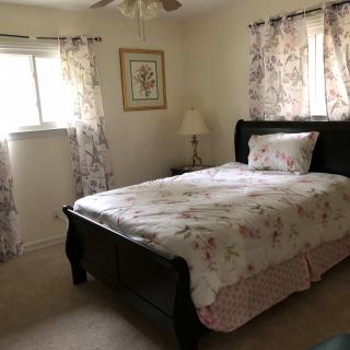 A cozy bedroom with floral decor and natural lighting.