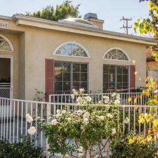 A cozy house with a front garden and white fence.