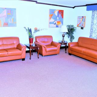 A bright living room with leather sofas, colorful artwork, and potted plants.