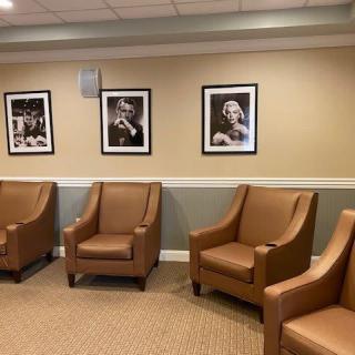 A cozy waiting room with brown leather chairs and black-and-white framed photographs on the wall.