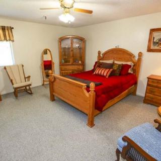 A traditional-style bedroom featuring wooden furniture and a cozy bed with red bedding.