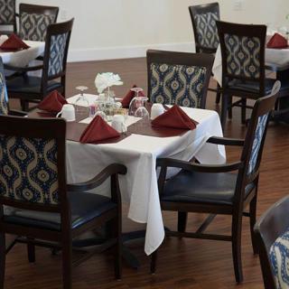 A restaurant dining area with elegantly set tables, featuring white tablecloths and red napkins.