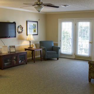 A cozy living room with a TV, armchair, and lamps.