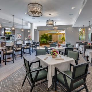 A modern and elegant dining area with neatly arranged tables and chairs, featuring stylish lighting fixtures.