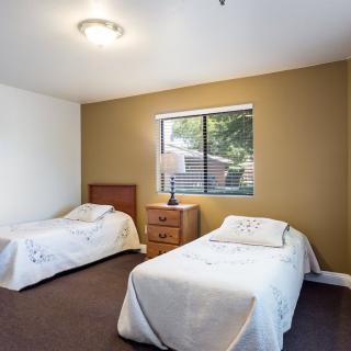 A cozy bedroom with two single beds, a central nightstand, and a window bringing in natural light.