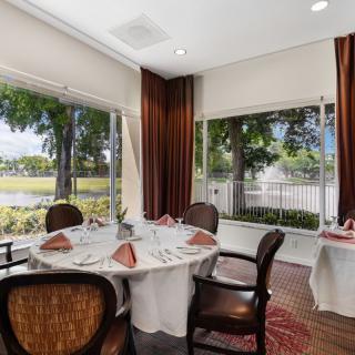 A cozy dining area with a round table and chairs, featuring large windows that offer a scenic outdoor view.