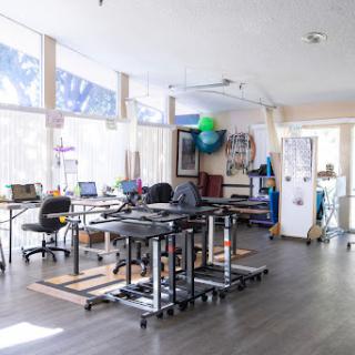 A bright and modern workspace with movable desks and large windows.