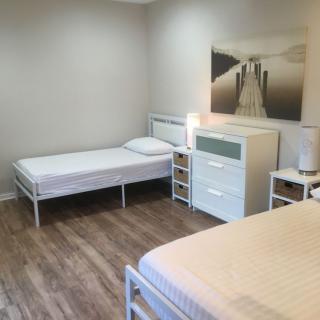 A minimalist bedroom with two beds, a dresser, and simple decor.
