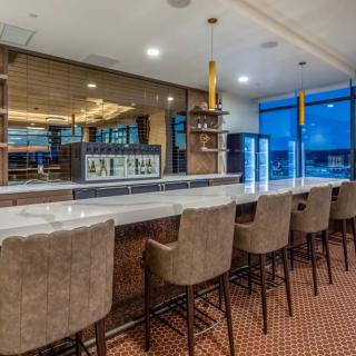 A modern bar interior with a long countertop and comfortable seating.