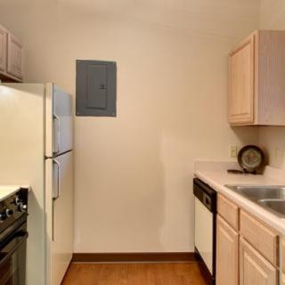 A compact apartment kitchen with modern appliances and wooden cabinets.