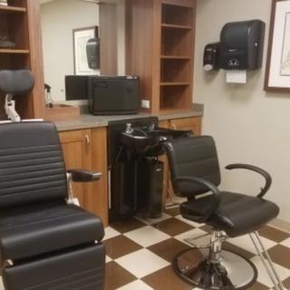 An empty barbershop with two chairs and a large mirror.