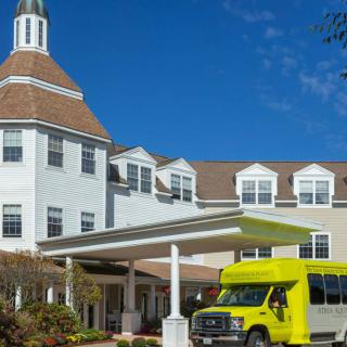 A bright green van parked in front of a large building with a covered entrance.