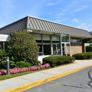 A modern commercial building with well-kept landscaping and a clear sky.