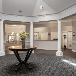 Bright and elegant lobby with decorative columns and a central table adorned with flowers.