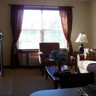 A cozy hotel room with a window, armchairs, and a lamp.
