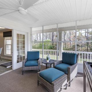 A cozy sunroom with wicker furniture and large windows overlooking a tranquil outdoor view.