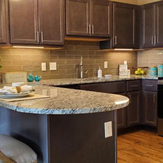 A modern kitchen with dark cabinets and a granite countertop.