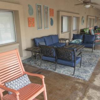 A cozy outdoor patio featuring comfortable seating, a decorative rug, and wall art.