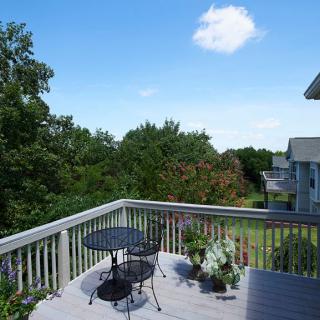 A sunny day on a backyard deck with patio furniture and potted plants.