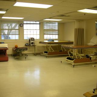 A rehabilitation room equipped with multiple therapy beds and equipment.