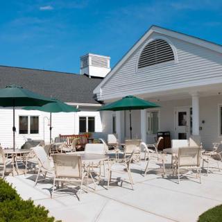 A sunny patio with chairs and umbrellas outside a building.