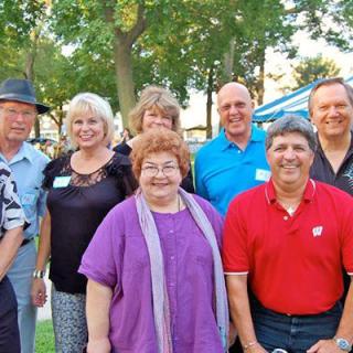 A group of adults posing for a photo outdoors in a park setting.