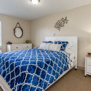 A cozy bedroom with a blue patterned bedspread, white furniture, and wall decorations.