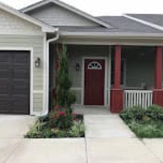 A cozy single-story house with a front porch and attached garage.
