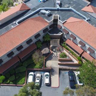 Aerial view of a building complex with a central courtyard and adjacent parking area.