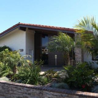A residential house featuring a modern architectural style with palm trees and a landscaped garden.