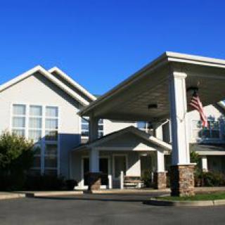 A front view of a large residential building with a covered entrance and an American flag.