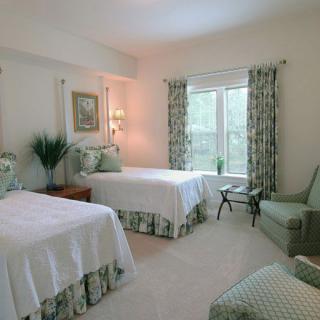 A cozy bedroom featuring twin beds with green accents and ample natural light.