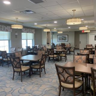 A spacious dining area with neatly arranged tables and chairs, illuminated by soft overhead lighting.