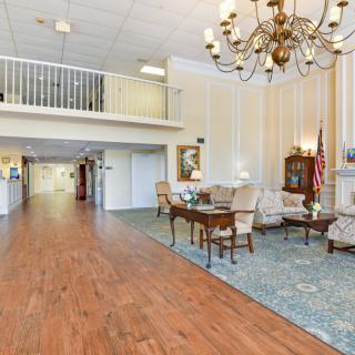 A spacious lobby with elegant decor, featuring a chandelier and comfortable seating area.