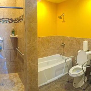 A modern bathroom with a bathtub and shower, featuring yellow walls and tile flooring.