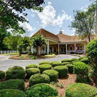A charming building surrounded by a well-maintained garden and lush greenery under a partly cloudy sky.