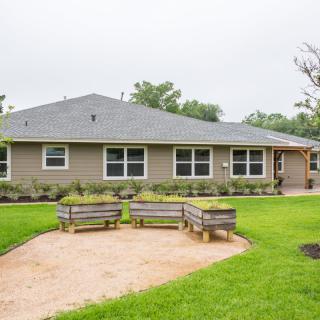 A suburban house with a well-maintained backyard featuring benches and lush greenery.