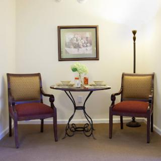 A cozy corner featuring two chairs, a small table with decorative items, and a lamp, perfect for relaxation.