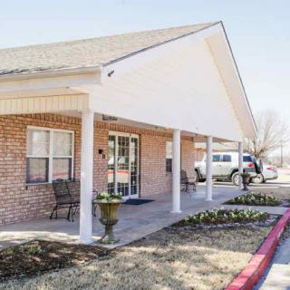 A brick building with a covered entrance and patio seating on a sunny day.