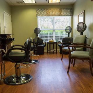 An empty hair salon featuring styling chairs and hair dryers.