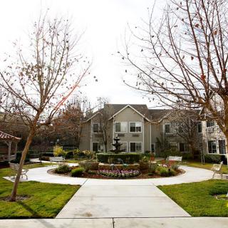 A view of an apartment complex with a landscaped walkway and bare trees.