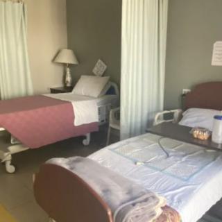 A hospital room with two beds separated by privacy curtains.