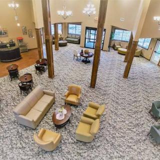 A spacious hotel lobby featuring comfortable seating, elegant chandeliers, and a patterned carpet.