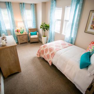 A cozy bedroom with bright natural light, featuring modern decor and comfortable furnishings.